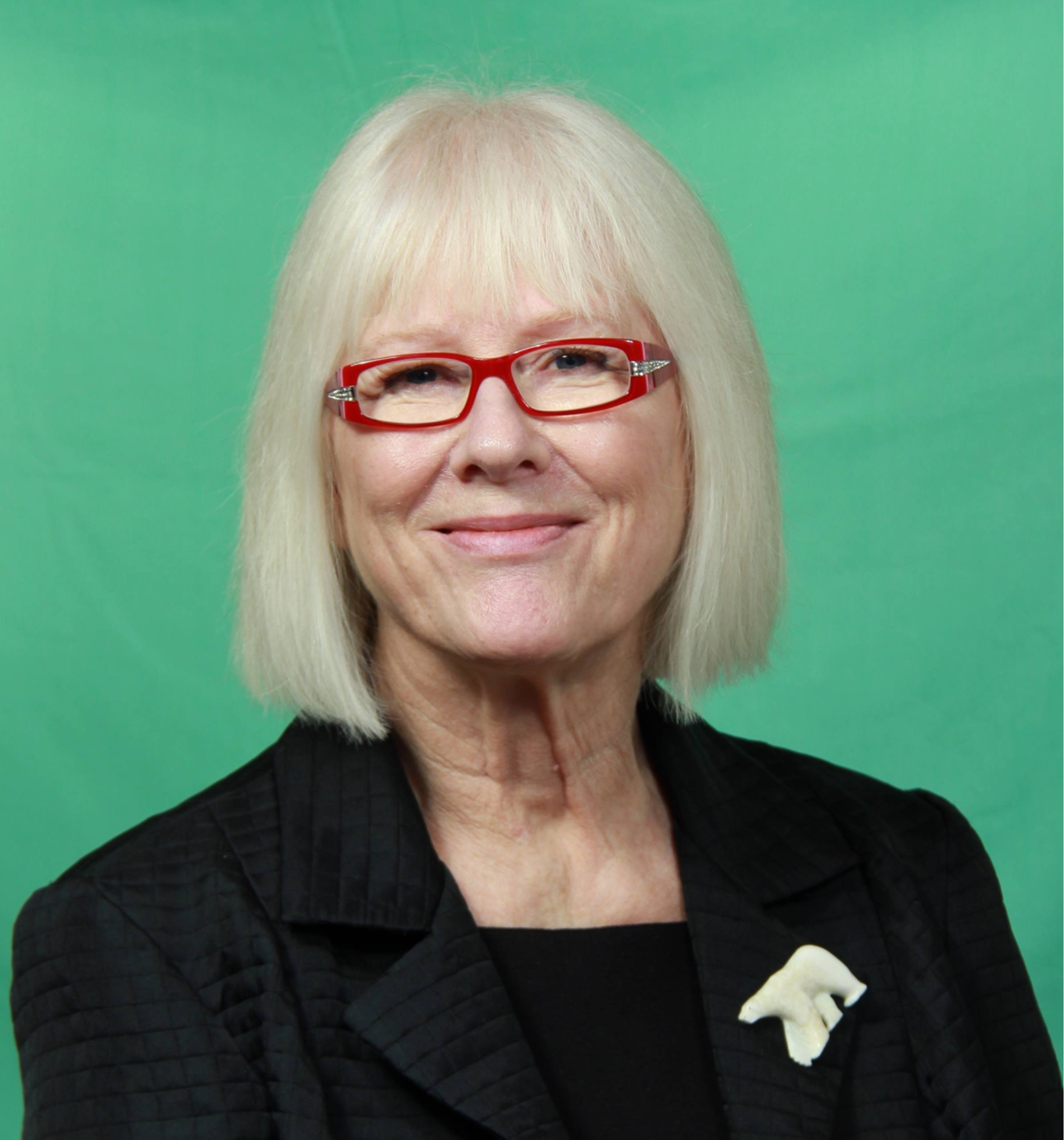 Tanny Nadon, volunteer, headshot of an older white woman with short white hair and red glasses in a black suit.